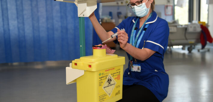 Deputy sister nurse Liz Warren putting needle into yellow sharps bin attached to trolley