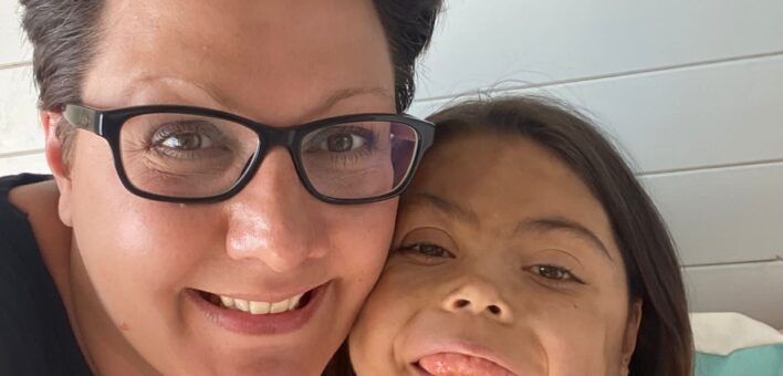 Dark-haired woman in glasses cuddling her daughter with dark-haired bob