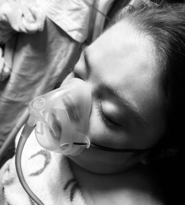 Child with oxygen mask on face and eyes closed