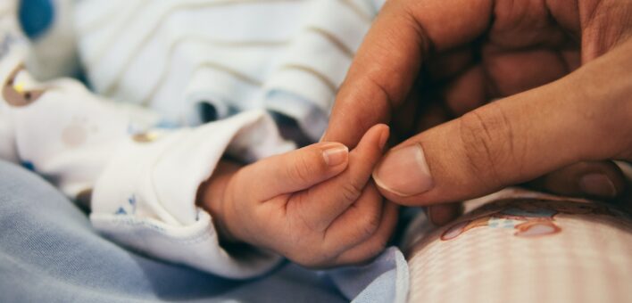 Newborn baby hand being held by adult hand