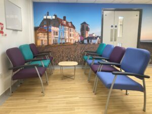 A waiting room with blue, green and purple chairs