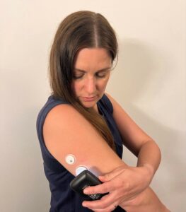 woman looking down at bare upper arm scanning it with mobile phone