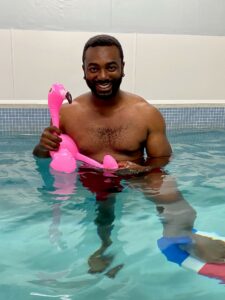 Man in swimming pool holding inflatable flamingo